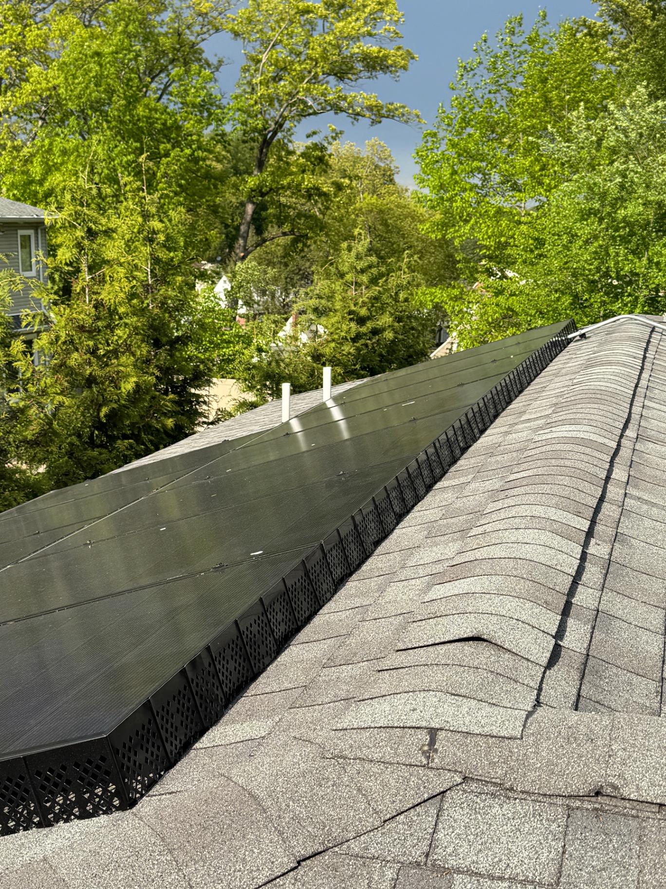 Black metal critter guard mesh installed along the edge of a rooftop solar array in Township of Washington, New Jersey