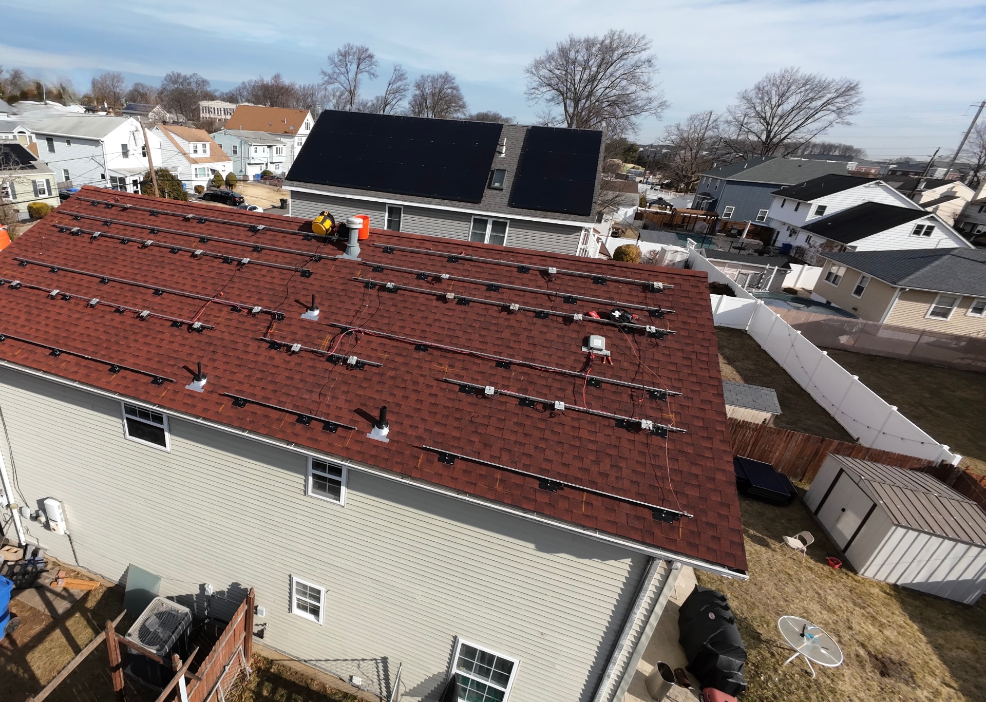 Aerial view of a red shingle roof with solar racking rails remaining after a full solar panel system removal