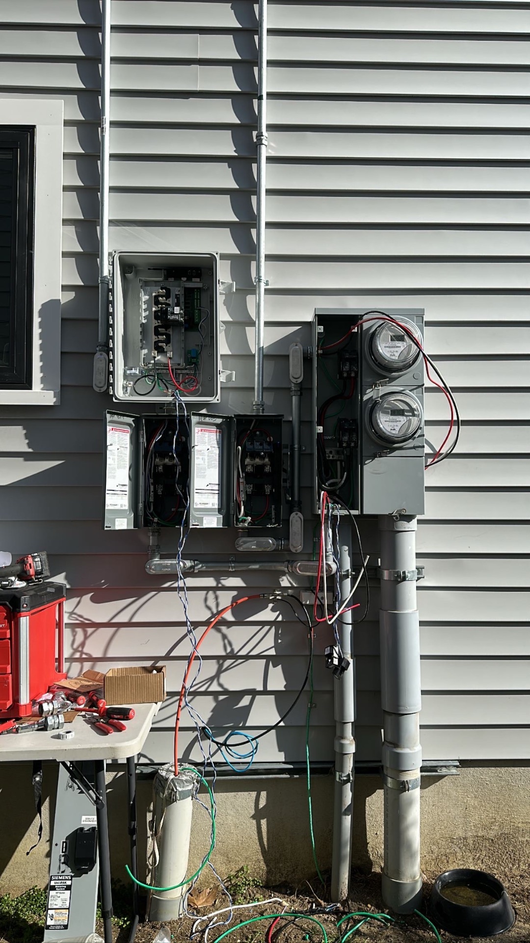 Open solar inverter, disconnects, and meter enclosures on the side of a home during inverter troubleshooting in Asbury Park, New Jersey