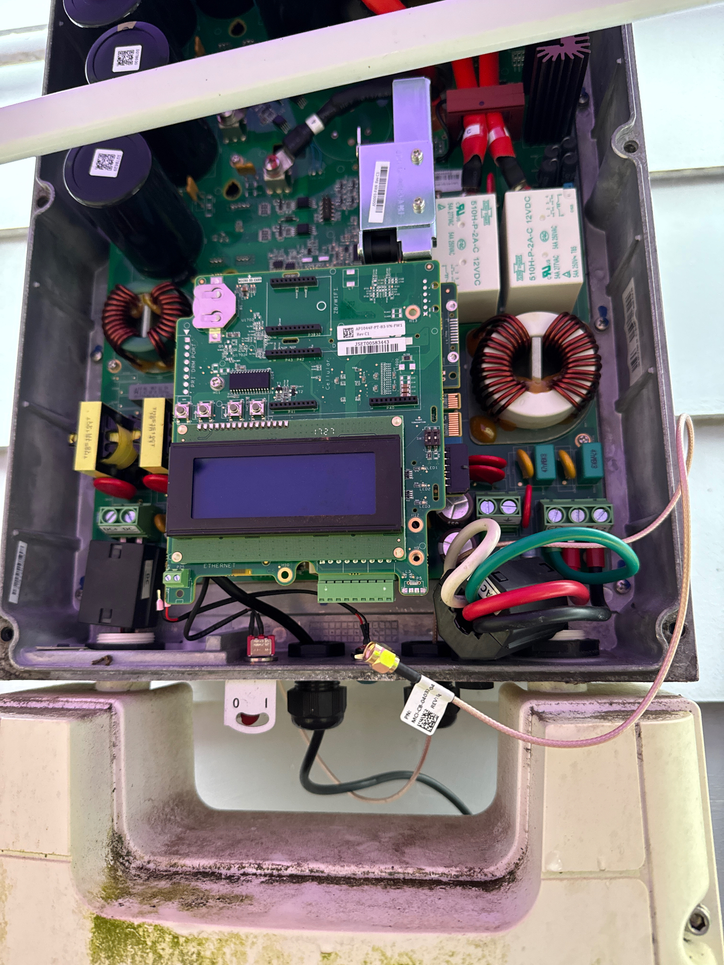 Opened solar inverter showing internal circuit boards, wiring, and components during troubleshooting in Monmouth County, NJ