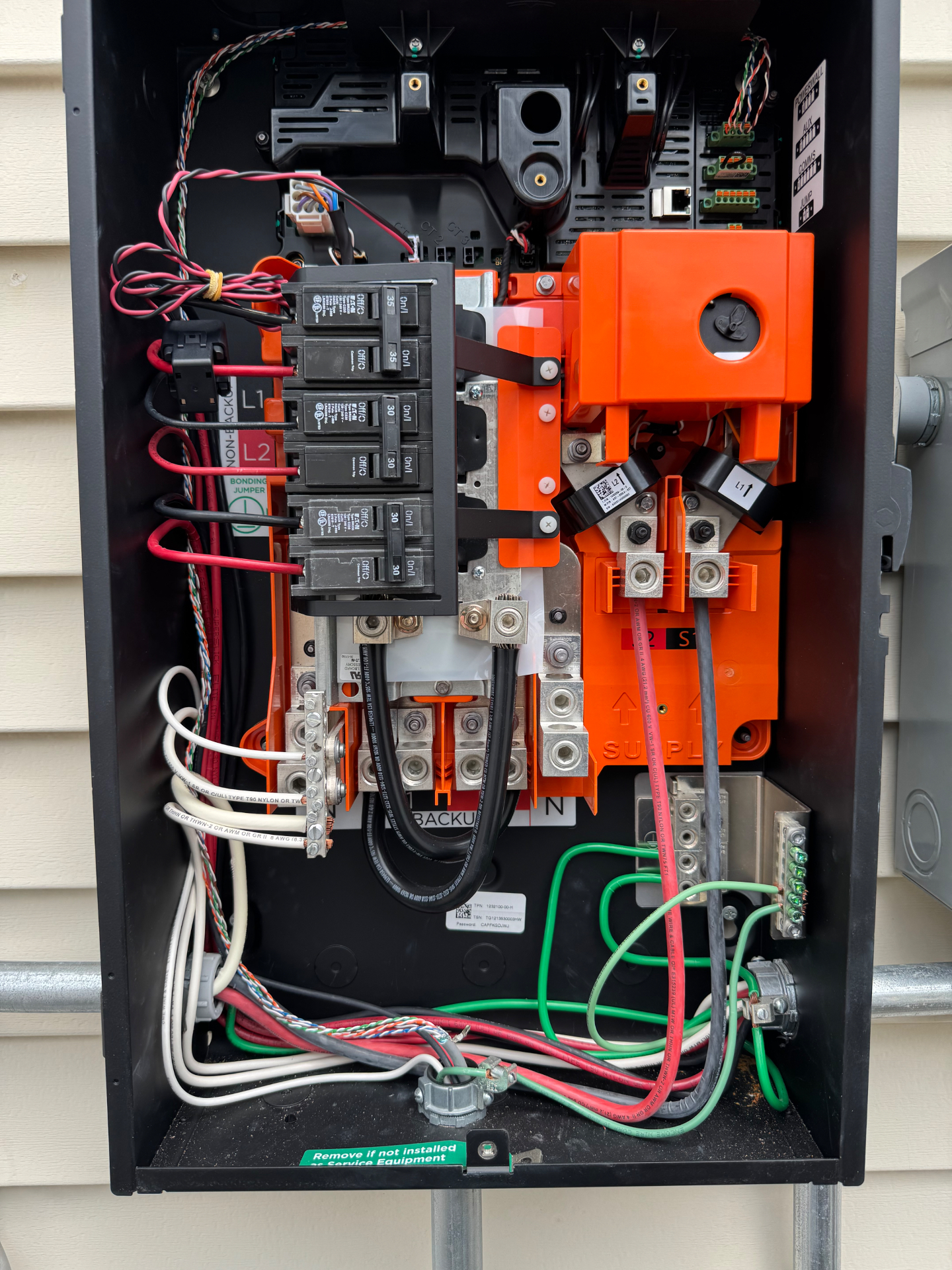 Open Tesla Backup Gateway enclosure with breakers and current transformers during troubleshooting