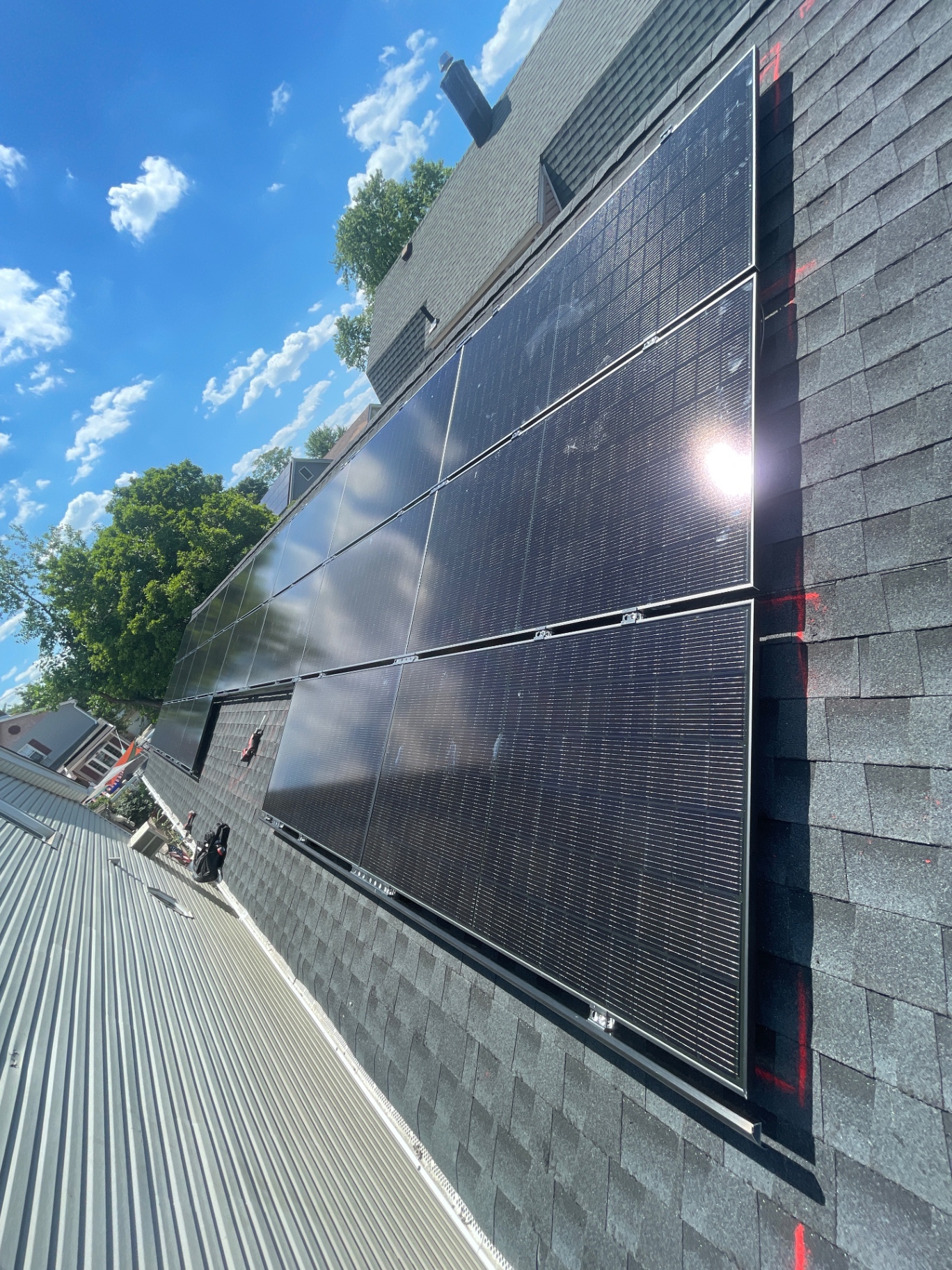 Close-up of a 22 panel all-black solar array being installed on a shingle roof in Elizabeth, New Jersey